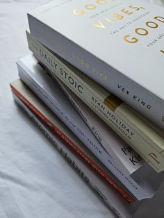 a stack of books sitting on top of a white table cloth covered bedding next to each other