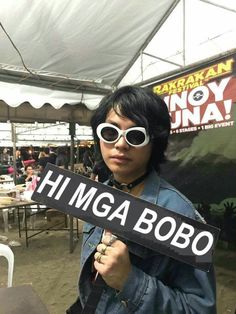 a person wearing sunglasses holding up a sign