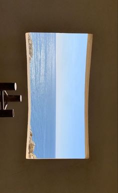 an open window overlooking the ocean with blue sky and water in it, as seen from below