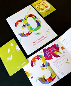 an assortment of colorful cards and envelopes on a black surface with butterfly logo in the middle