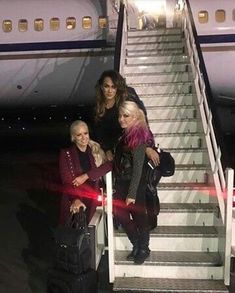 three women standing at the bottom of an airplane stairs