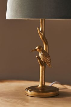 a lamp that is on top of a table with a bird sitting on the branch