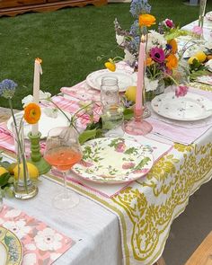 a table set with plates, glasses and candles for a formal dinner or party in the garden