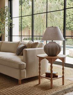 a living room with a couch, table and large window overlooking the pool in the background