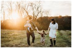 a family holding hands and walking through an open field at sunset with the sun behind them