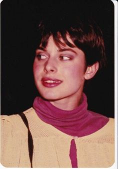 a woman with short hair wearing a pink scarf