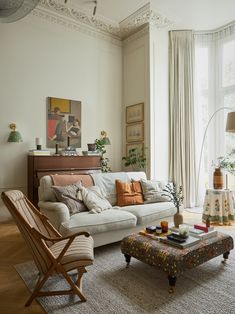 a living room filled with furniture and a painting hanging on the wall above it's windows