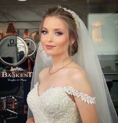 a woman in a wedding dress posing for the camera with her veil pulled back over her head