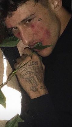 a man with tattoos on his arms and arm is holding a rose in front of his face