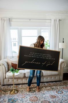 a woman sitting on top of a couch holding a sign