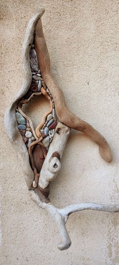 a piece of driftwood with rocks and shells embedded in it on the side of a building