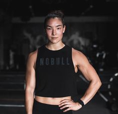 a woman standing with her hands on her hips wearing a black top that says nobull