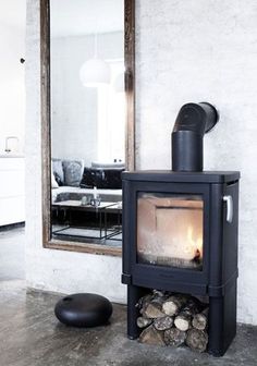 a wood burning stove sitting inside of a living room next to a mirror on the wall