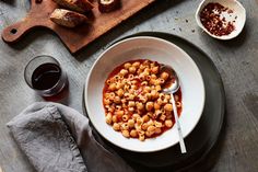 a white bowl filled with pasta next to bread on top of a wooden cutting board