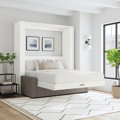 a white bed sitting on top of a wooden floor next to a potted plant