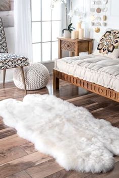 a white sheepskin rug on the floor in front of a couch, chair and ottoman