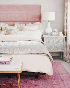 a bedroom with a pink headboard and white bedding on top of a purple rug