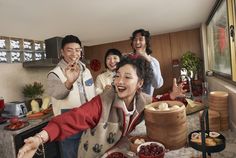 a group of people standing around a table with food and drinks in front of them