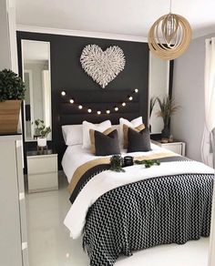 a black and white bedroom with lights on the headboard, bedding and pillows