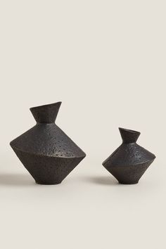 three black vases sitting next to each other on a white surface with no one around them