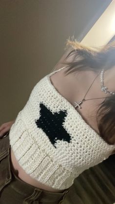 a woman wearing a white crochet top with a black bird on it's back