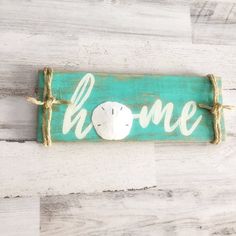 a wooden sign that says home with a sand dollar on it and rope around the edge