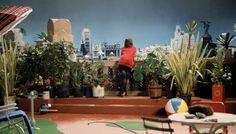 a woman is sitting on the steps in front of some plants and potted plants