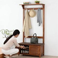 a woman kneeling down next to a coat rack