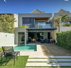 a house with a swimming pool in front of it and some lawn chairs on the side