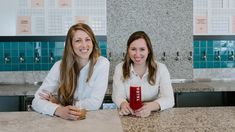 two women sitting at a counter with drinks