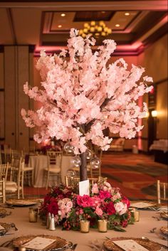 an elegant centerpiece with pink flowers and greenery is displayed on a round table