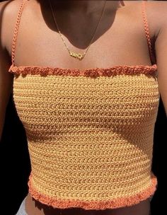 a close up of a woman wearing a yellow and orange top with an inscription on it