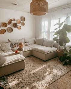 a living room filled with lots of furniture and plants on the wall next to a large window