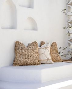 three pillows are sitting on a white shelf