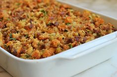 a white casserole dish filled with stuffing and toppings on a wooden table