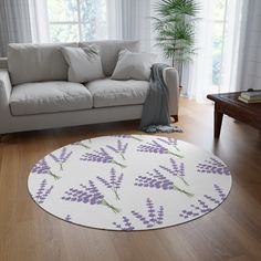 a living room with a white couch and purple flowers on the rug in front of it