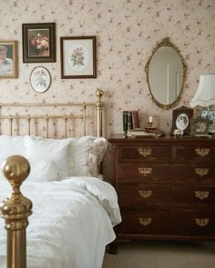 there is a bed and dresser in this room with floral wallpaper on the walls