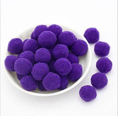 purple pom poms in a white bowl