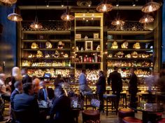 people sitting at tables in a bar with lots of bottles on the shelves behind them