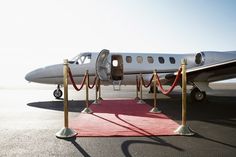 an airplane is parked on the runway with a red carpet and rope barriers around it