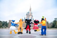 three people in mickey mouse costumes standing next to each other