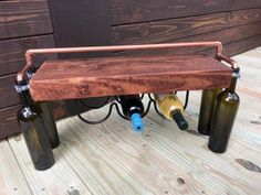 three wine bottles are connected to the back of a bench with copper piping on it