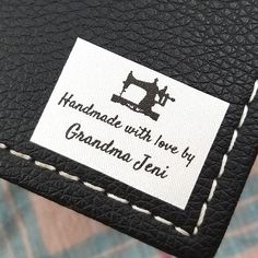 a close up of a label on a black leather case with white stitching that says handmade with love by grandma jean