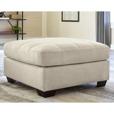 a beige ottoman sitting on top of a rug