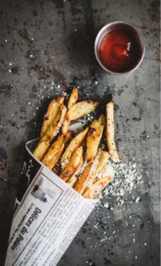 some french fries and a cup of tea are on the table next to a newspaper