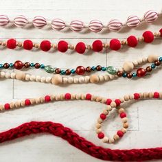 some beads are laying next to each other on a table with red and white yarn