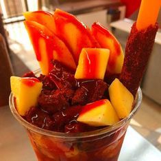 a cup filled with fruit and sauce on top of a table