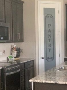 a kitchen with granite counter tops and black cabinets, along with a pantry sign on the door