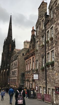 people are walking down the street in front of old buildings