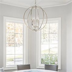 a dining room table with two chairs and a chandelier hanging from the ceiling